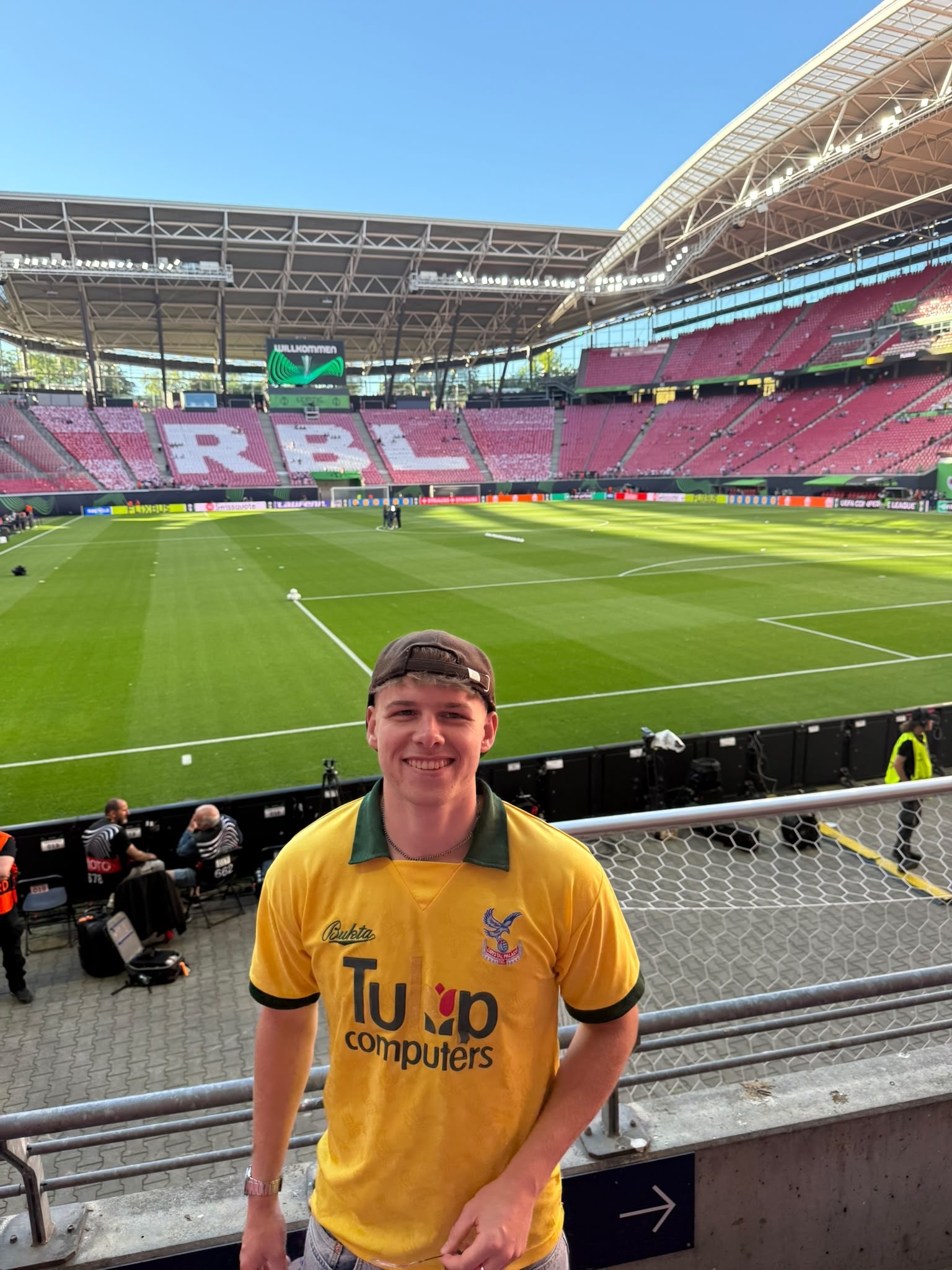 Zac at a football stadium, wearing a yellow Crystal Palace shirt